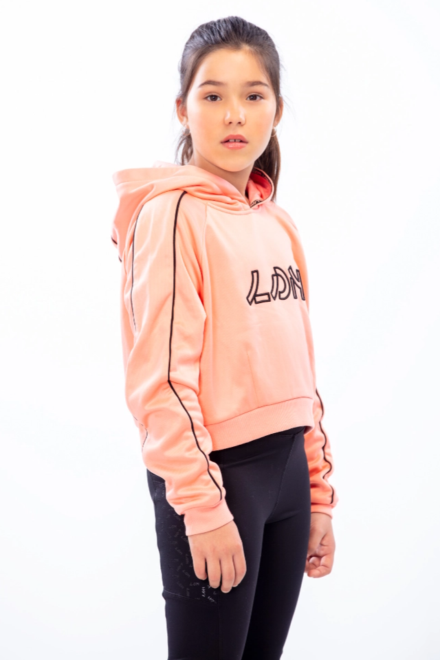 Side profile of kid looking at camera, wearing a pink with black details hoodie and black pants