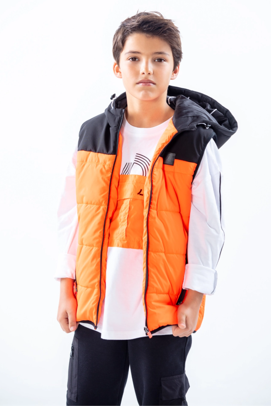 LOSAN- Collection TRY & GO, kid standing looking at camera wearing a white sweat with orange design and a orange and black sleeveless jacket