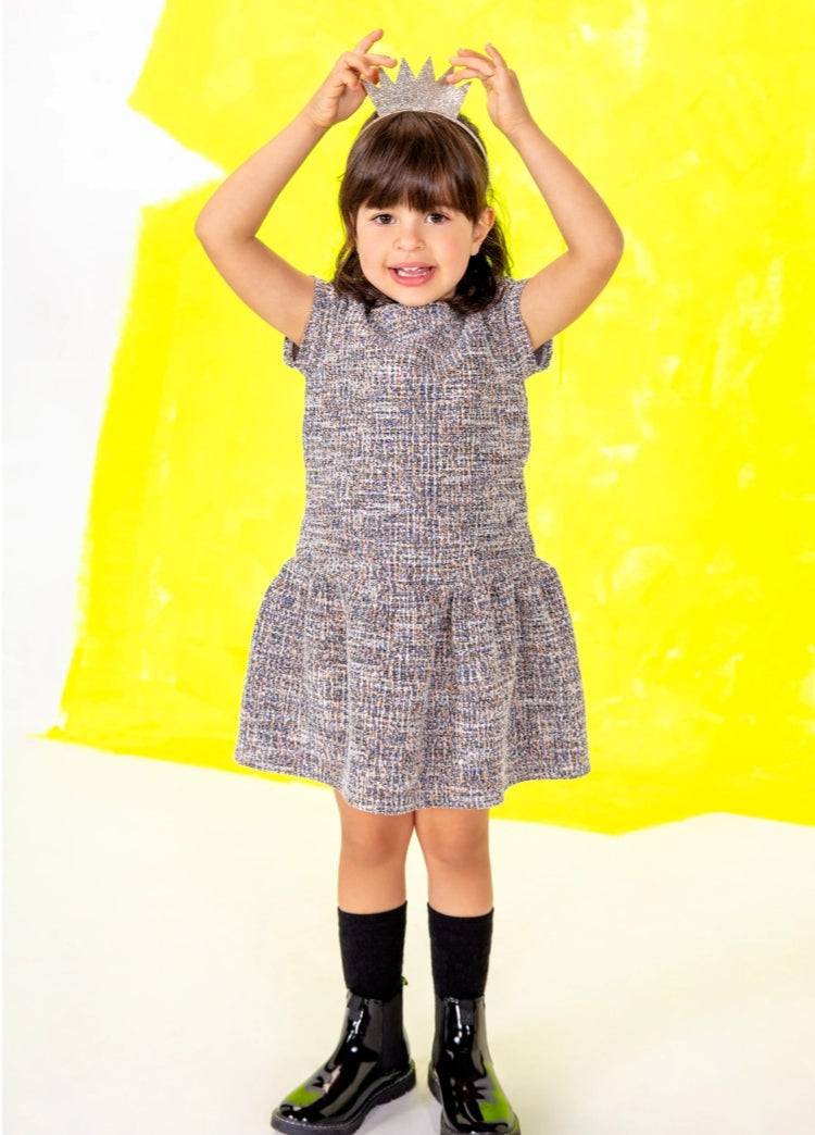 LOSAN - Stella Chic collection, Kid standing up touching a crown on top of her head, while wearing a grey dress and black boots
