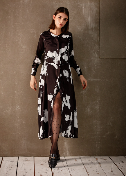 LOSAN - woman leaning against wall, wearing a black and white printed dress