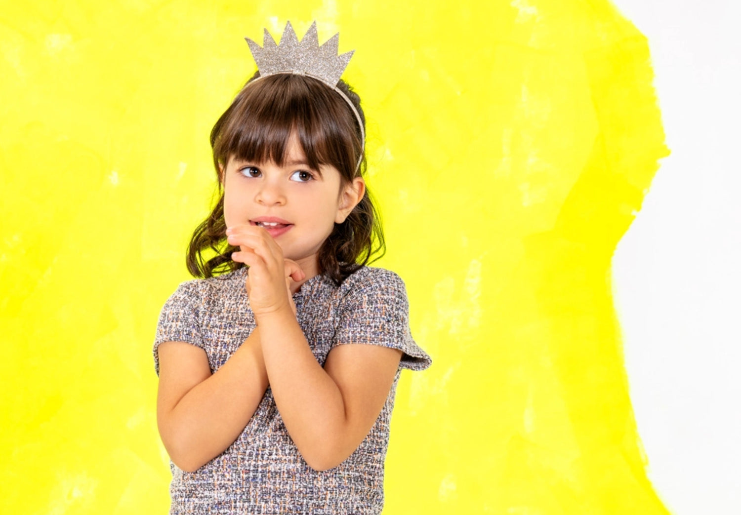 Portrait of little kid wearing a crown with a grey dress