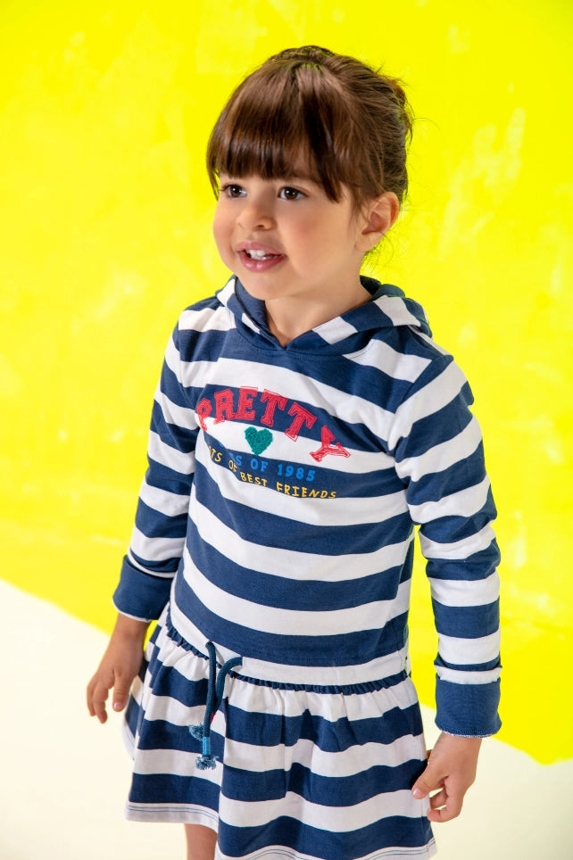 little kid standing wearing a striped shirt and skirt combo